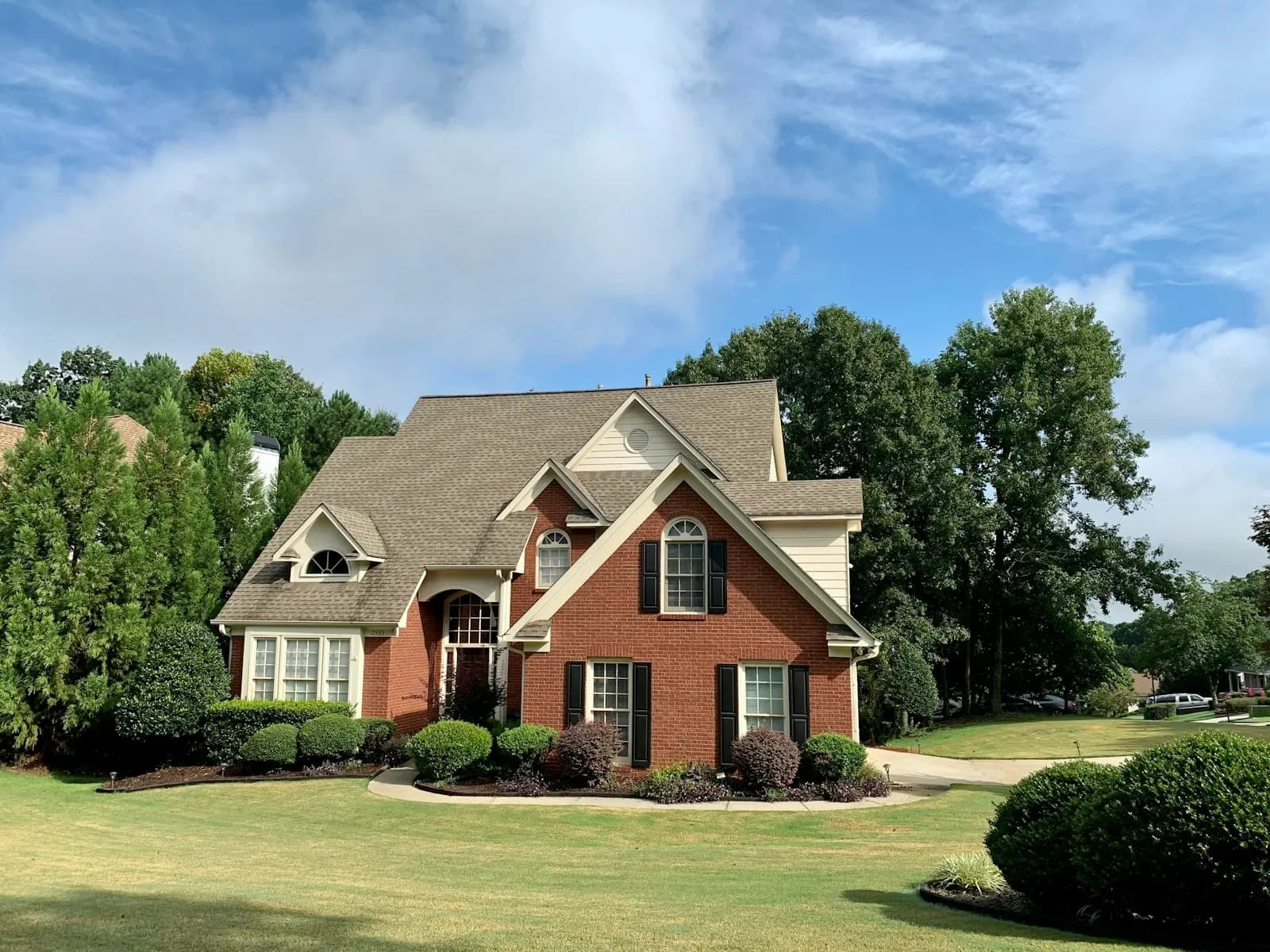 A brick two-story home surrounded by trees